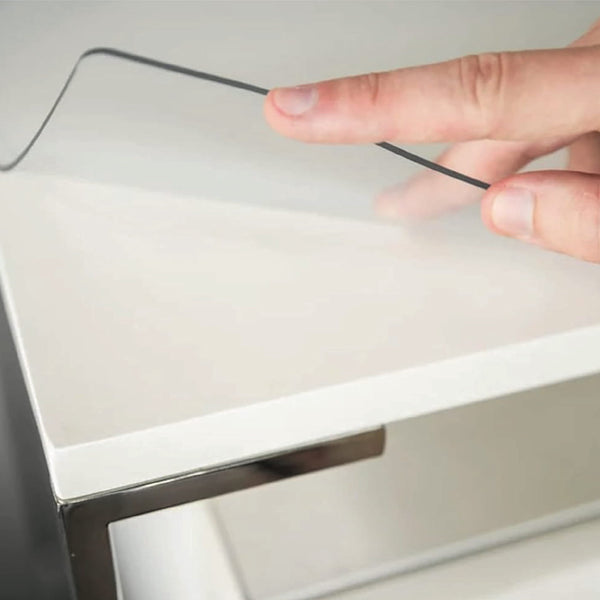 Hand lifiting clear table cover to show clean protected table underneath. Crystal